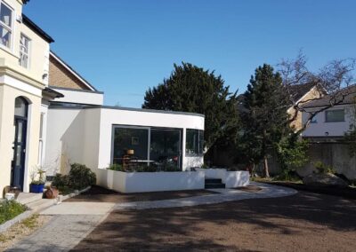 Contemporary white rear extension with large corner glazing and raised planter in landscaped garden