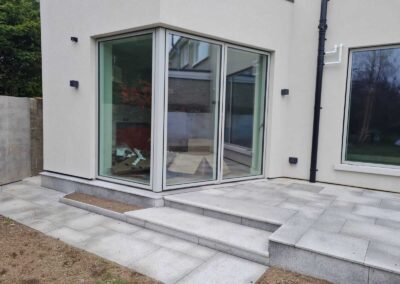 Modern corner glass extension with large sliding doors and newly installed granite patio steps