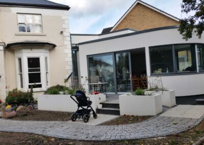 Modern rear house extension with curved exterior wall, large sliding glass doors and landscaped patio