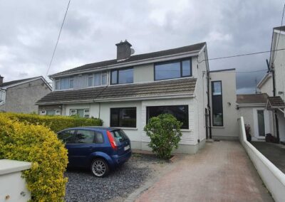 Modernised semi-detached house with upgraded front facade, large black-framed windows, and newly insulated exterior