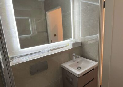 Renovated bathroom with LED backlit mirror, wall-hung toilet and compact vanity unit — Glanmore Construction