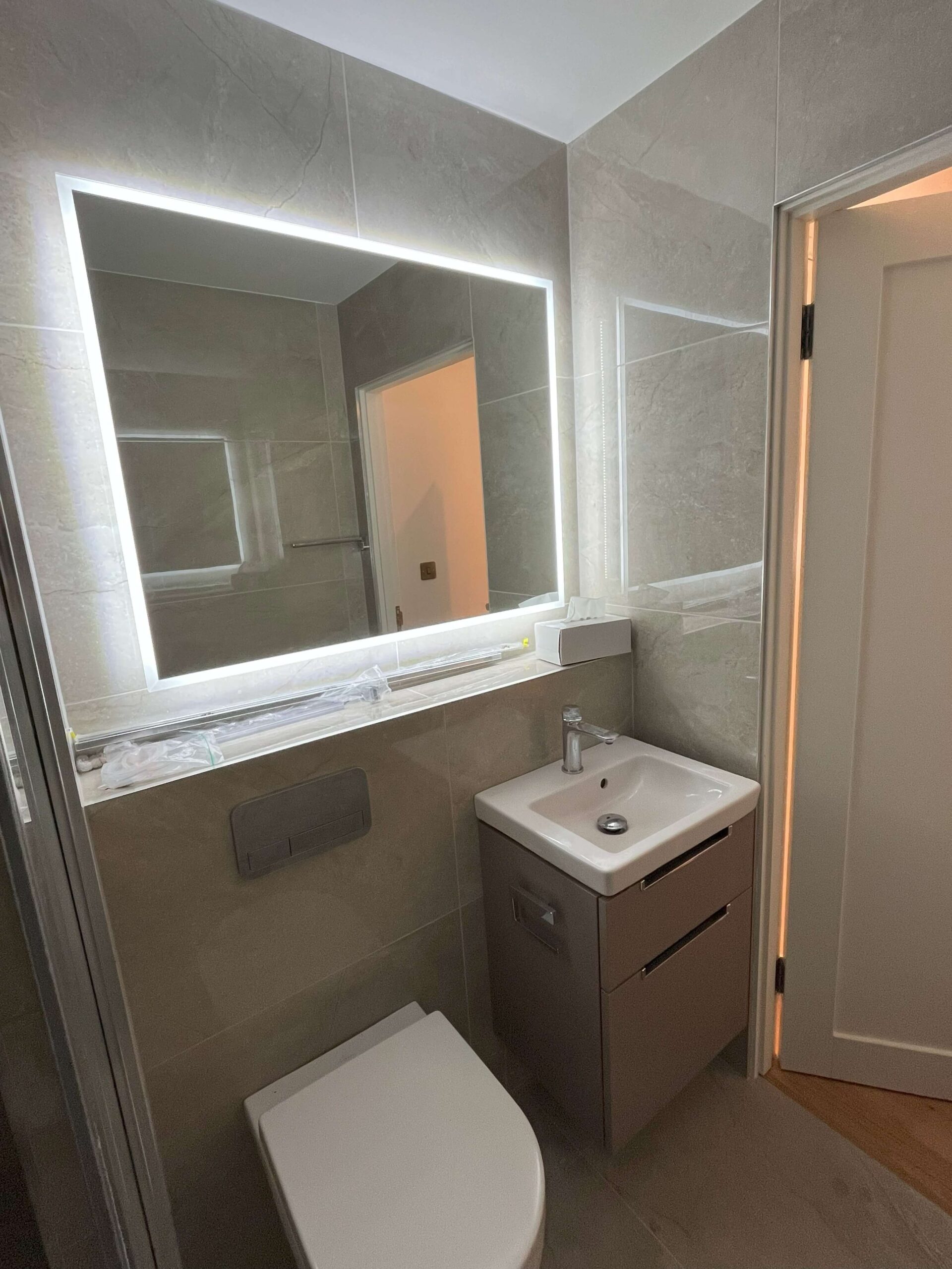alt="Fully refurbished bathroom with LED mirror, built-in cistern and modern washbasin cabinet"