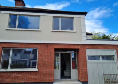 Renovated front facade featuring red brick, cream render, modern grey windows, and upgraded entrance door