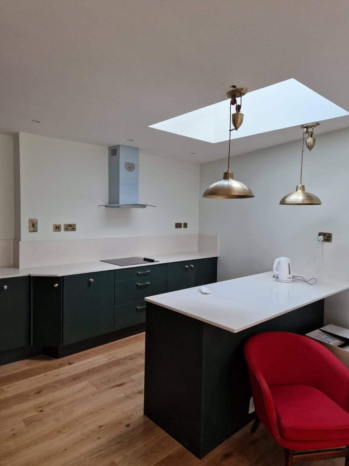 alt="Modern kitchen design with built-in hob, quartz countertops, dark cabinetry and central island"